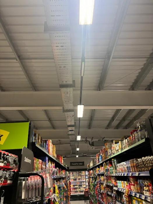 Overhead cable containment and lighting above a retail aisle