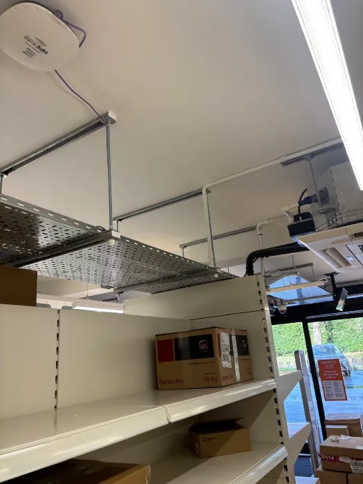 Cable basket run installed above stockroom shelving